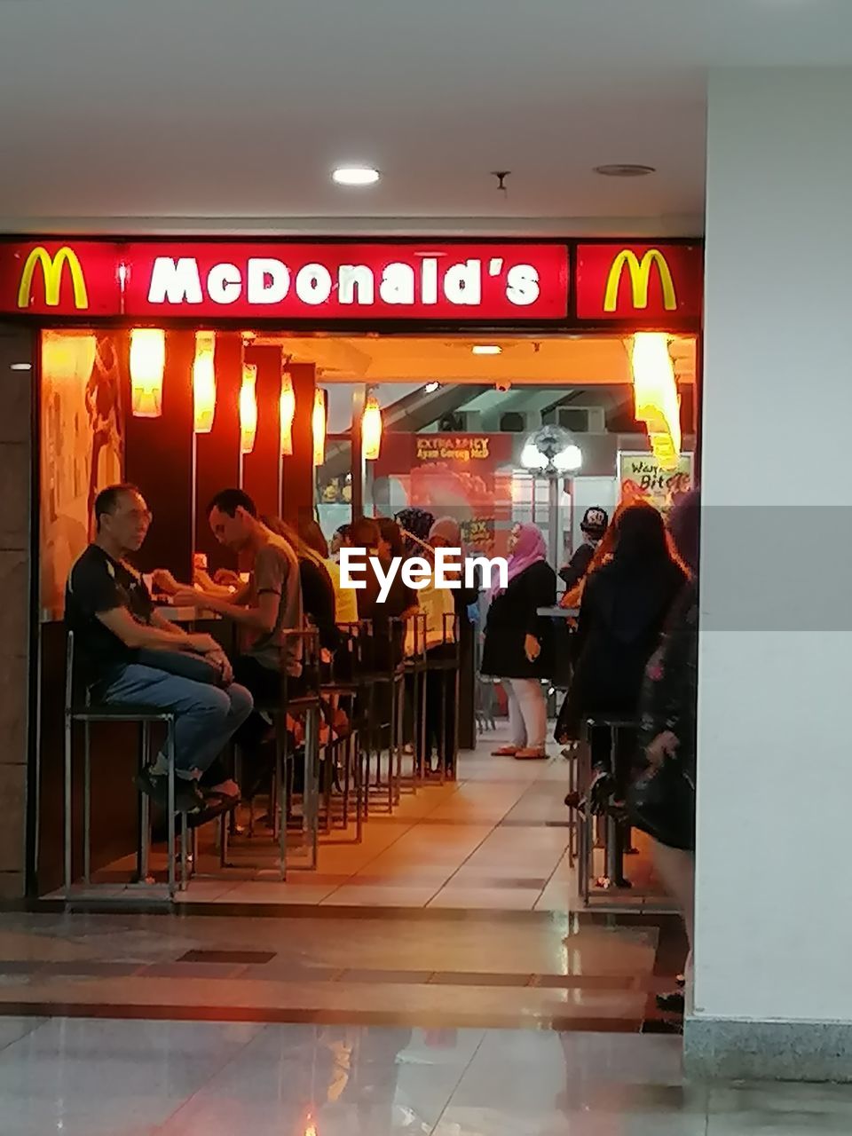 PEOPLE AT RESTAURANT IN ILLUMINATED CAFE