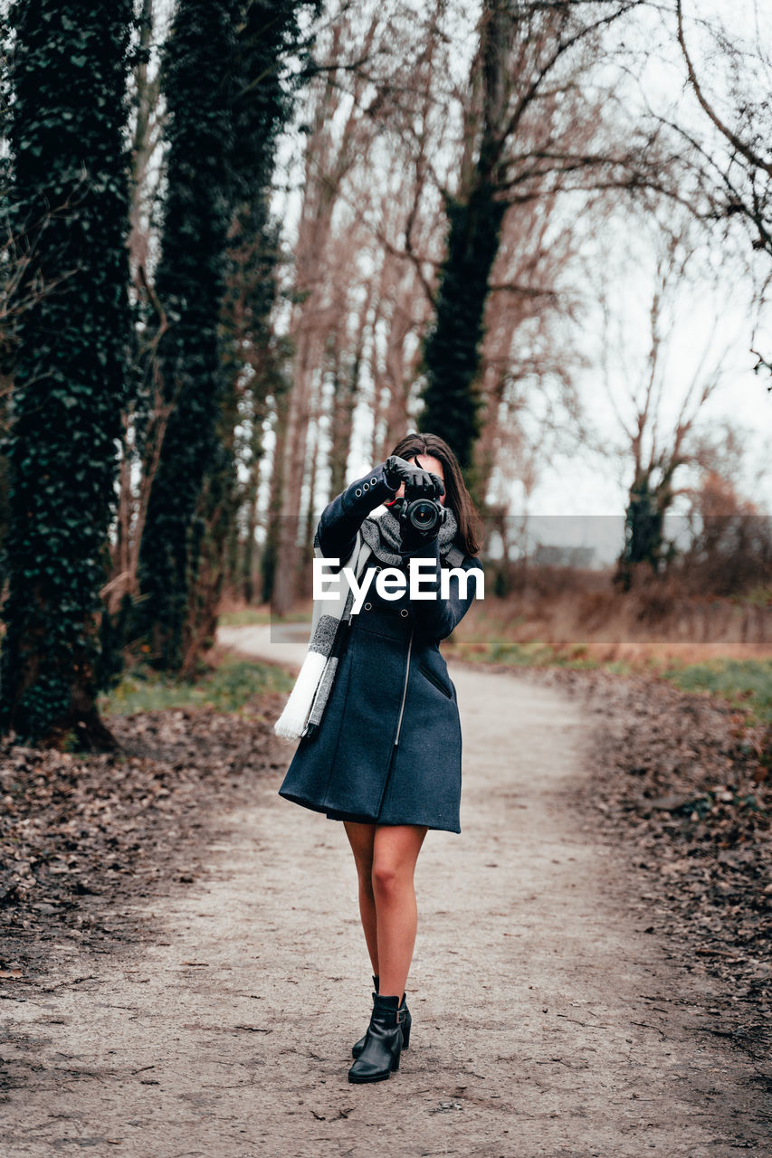 Full length of woman photographing in forest