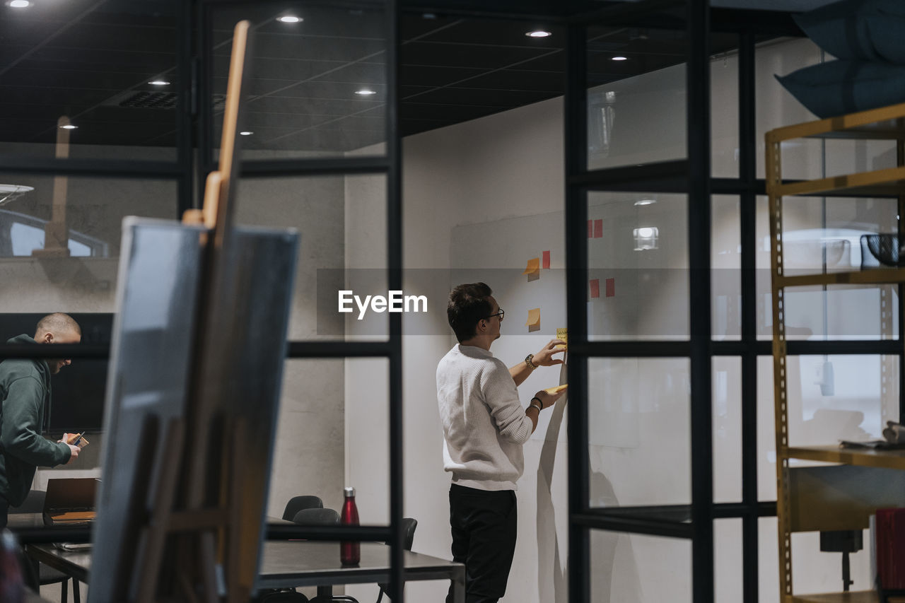 Young businessman brainstorming on adhesive notes at creative office