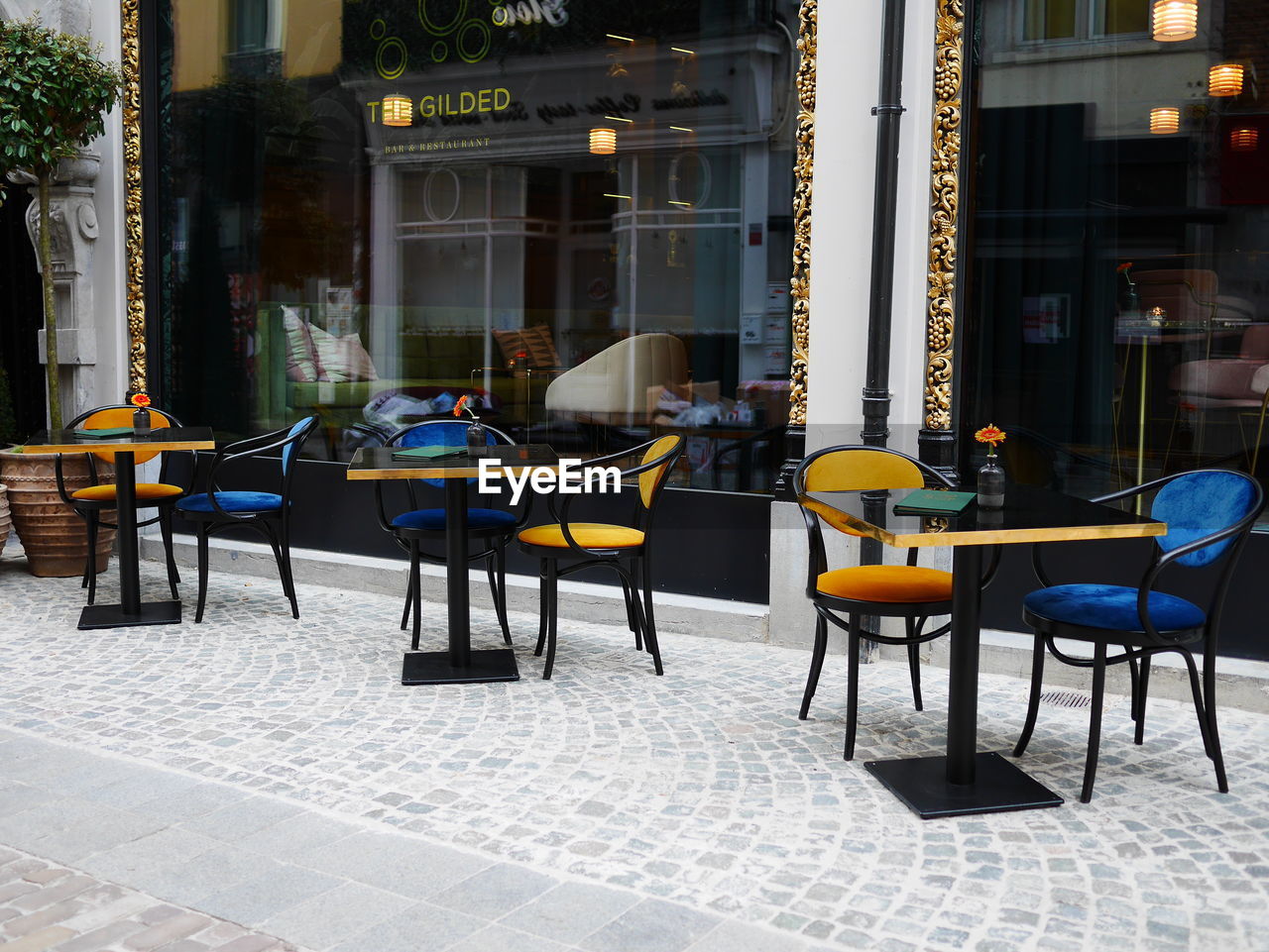 CHAIRS AND TABLES AT SIDEWALK CAFE AGAINST BUILDINGS IN CITY