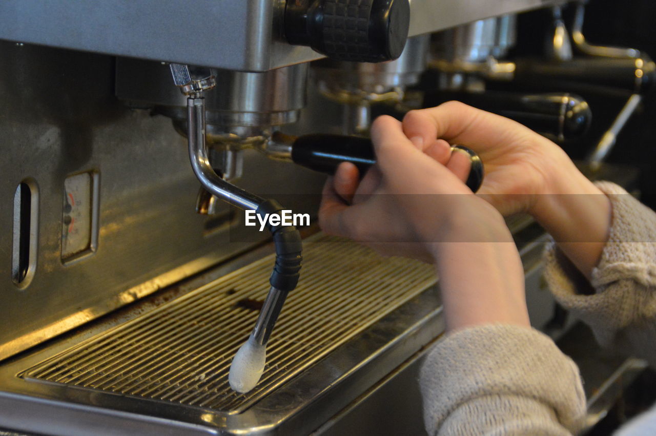 Cropped image of barista using espresso maker in cafe