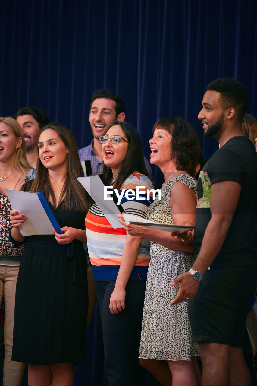 Multi-ethnic people singing in choir on school stage