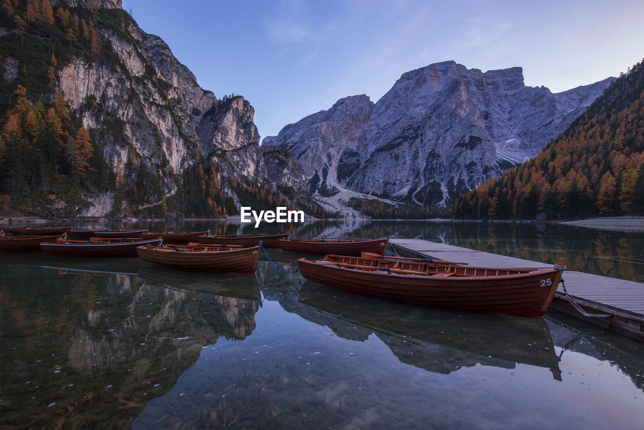 Boats moored in lake by mountains against sky at lago di braies in dolomites mountains 