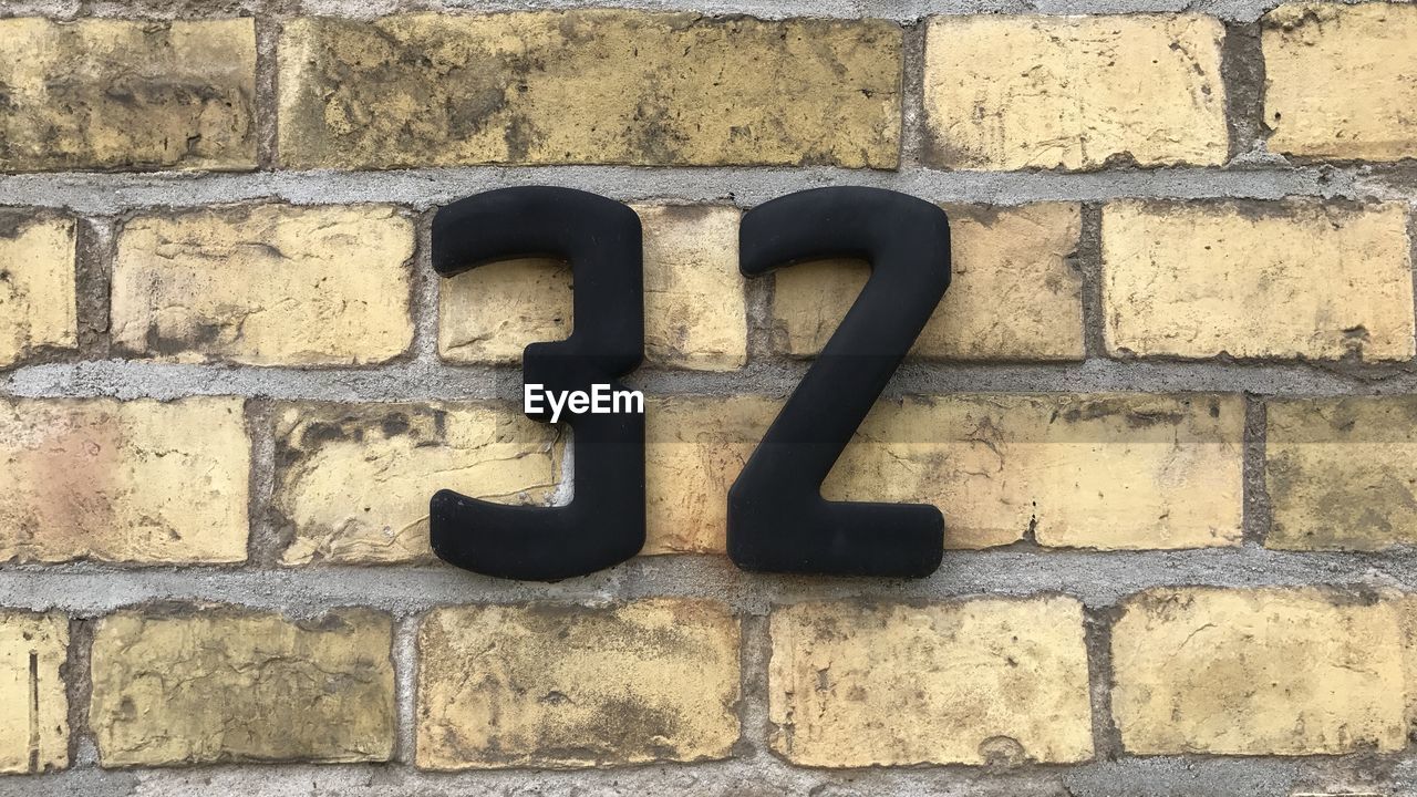 Close-up of number 32 on brick wall