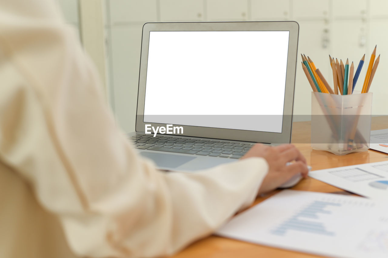 Midsection of woman using laptop at office