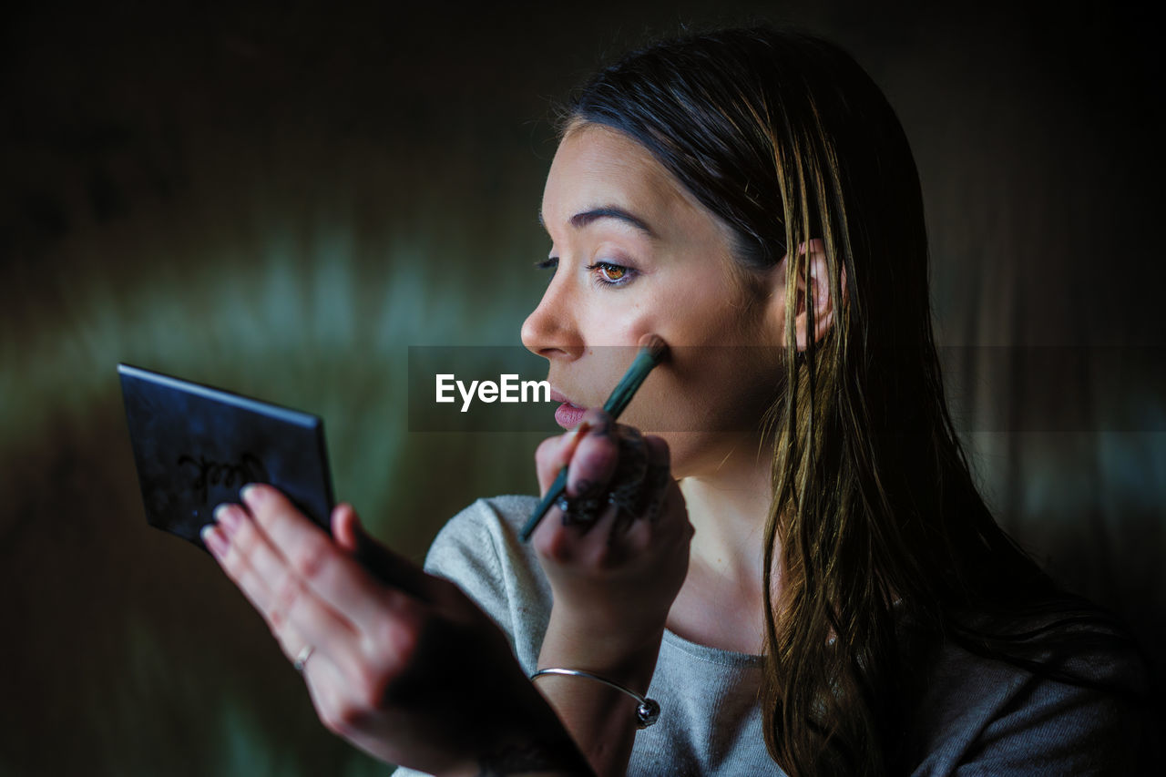 PORTRAIT OF YOUNG WOMAN USING MOBILE PHONE IN LAPTOP