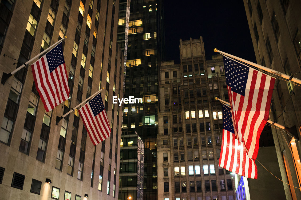 Low angle view of american flags on buildings at night
