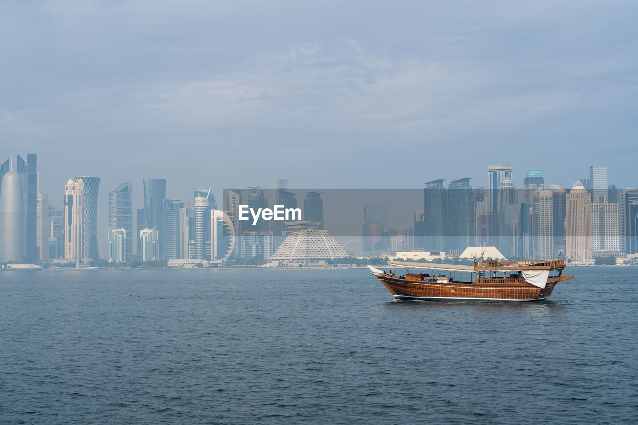 A traditional dhow in doha, qatar with the city's modern skyline in the background.