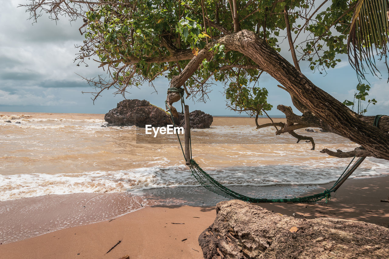 An abandoned hammock on an empty beach in axim ghana west africa.