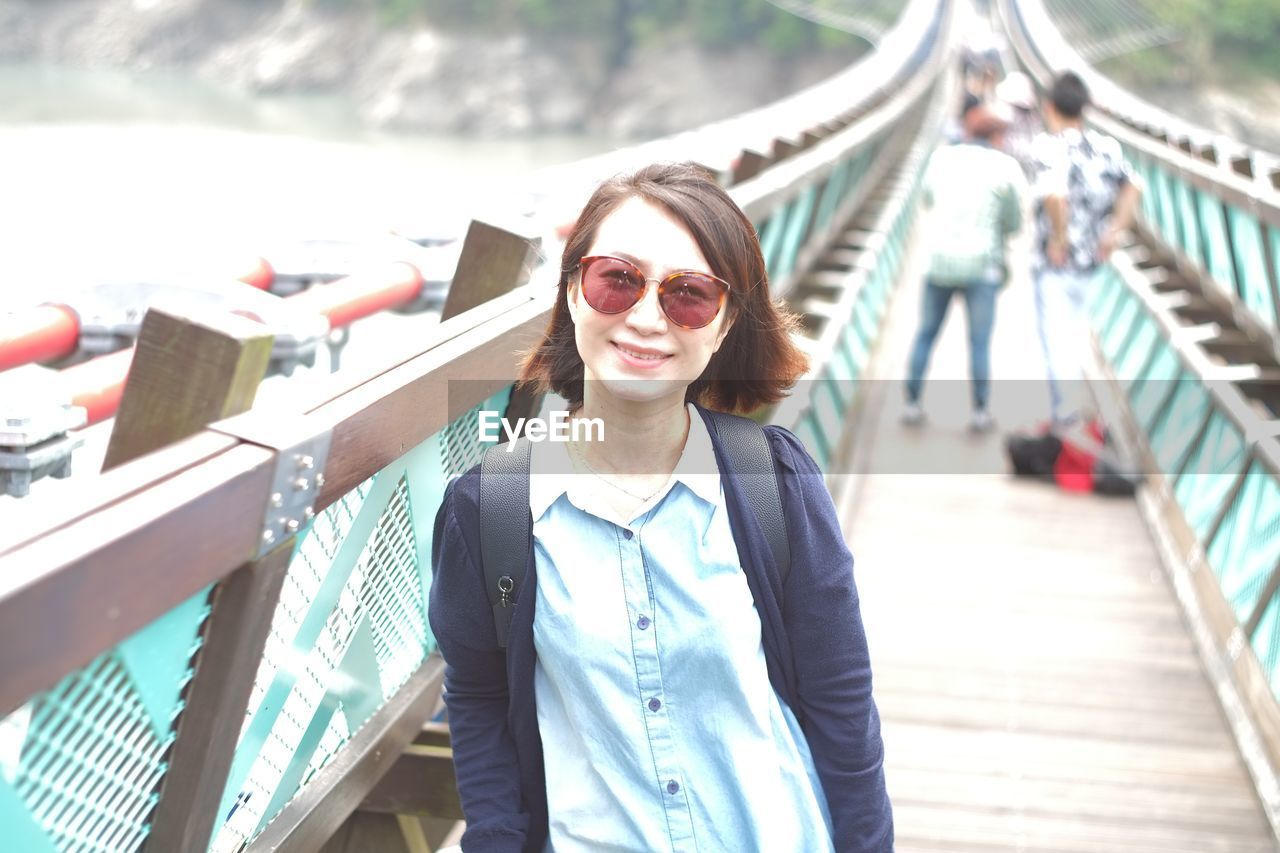 Smiling woman standing on footbridge