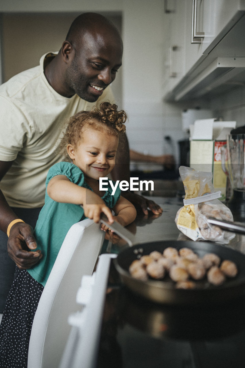 Happy girl helping father cook meal