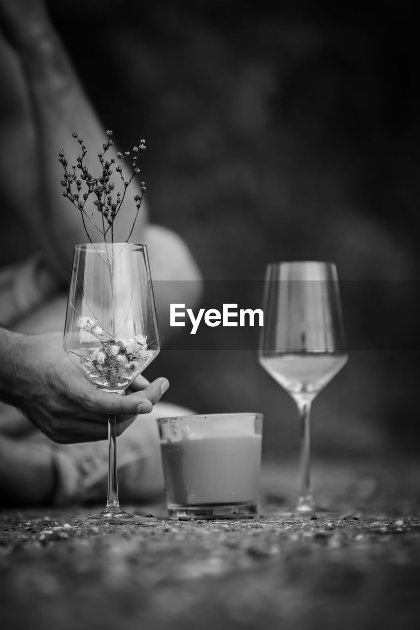 Black and white photo to a candle between 2 wine glasses and a hand