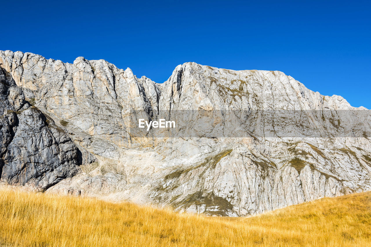 low angle view of rock formations against clear blue sky