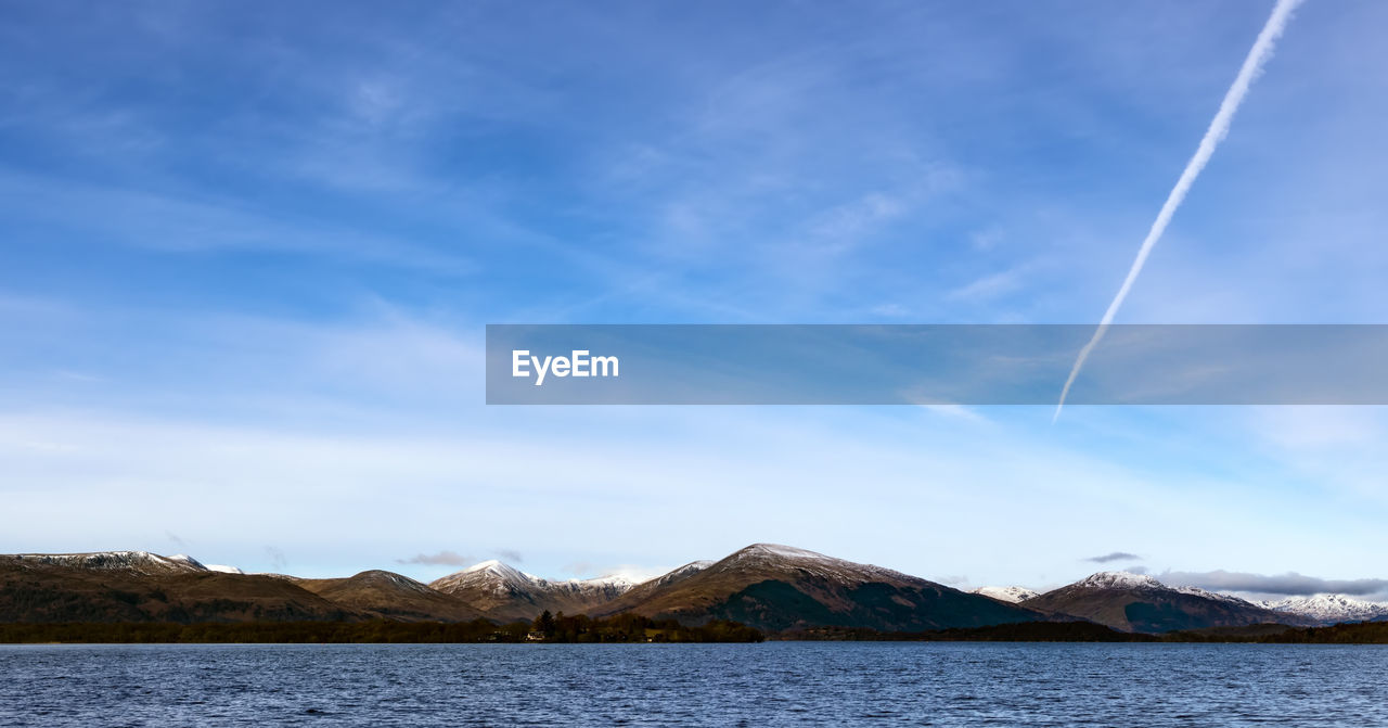 Scenic view of lake and mountains against blue sky