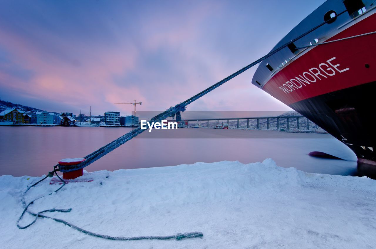 ROAD SIGN BY SNOW COVERED CITY AGAINST SKY