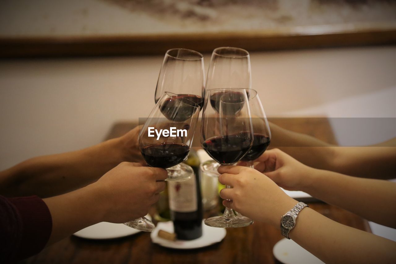 Cropped hands of people toasting red wine at restaurant