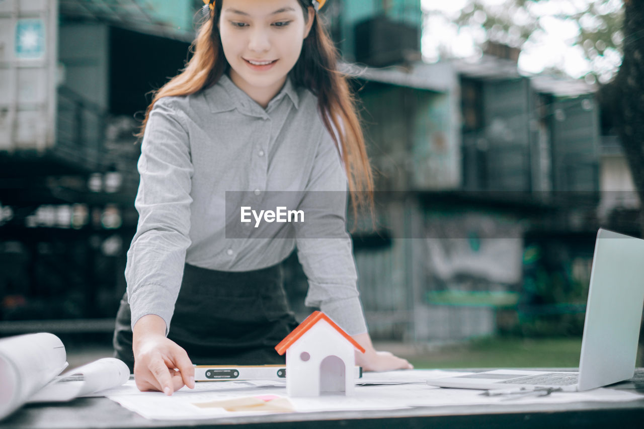 Young engineer working over blueprint while standing outdoors