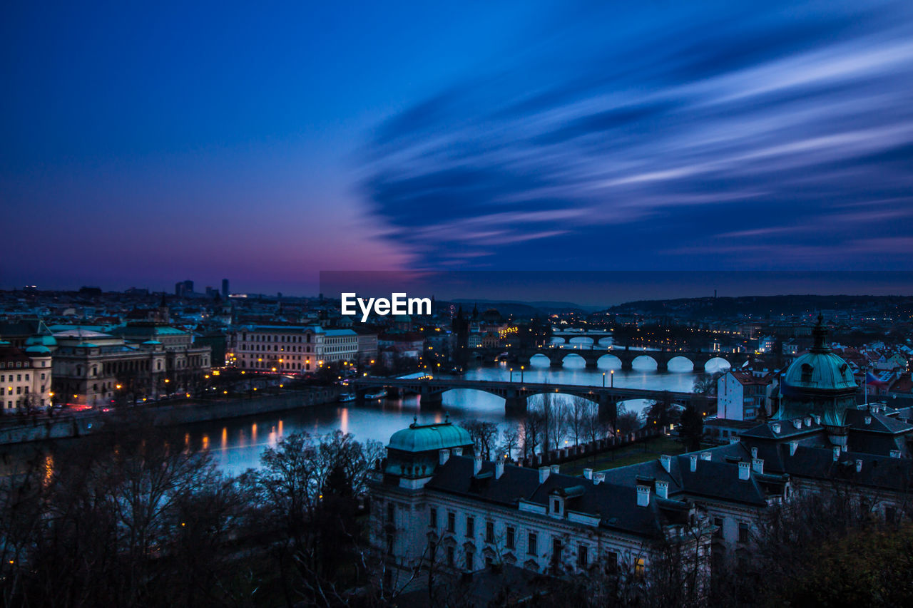 Charles bridge over vltava river against sky in city at dusk