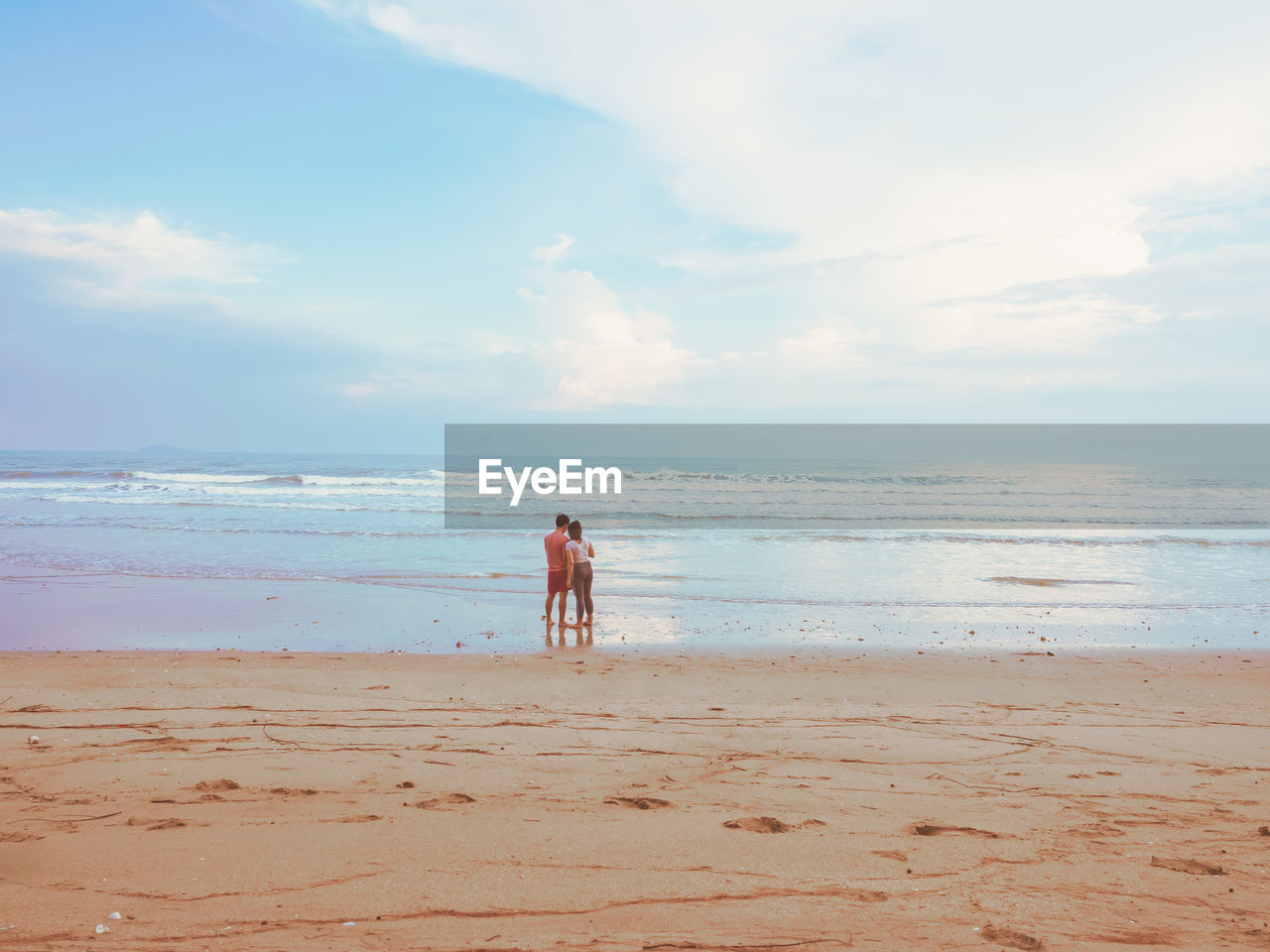 Happy romantic couple enjoying beautiful sunset walk on the beach. pastel colors tone