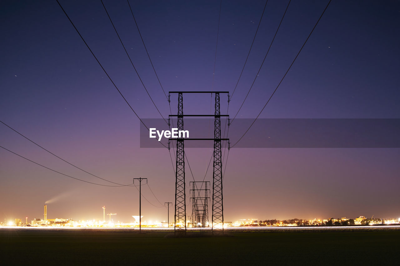 Silhouette of electricity pylon at dusk