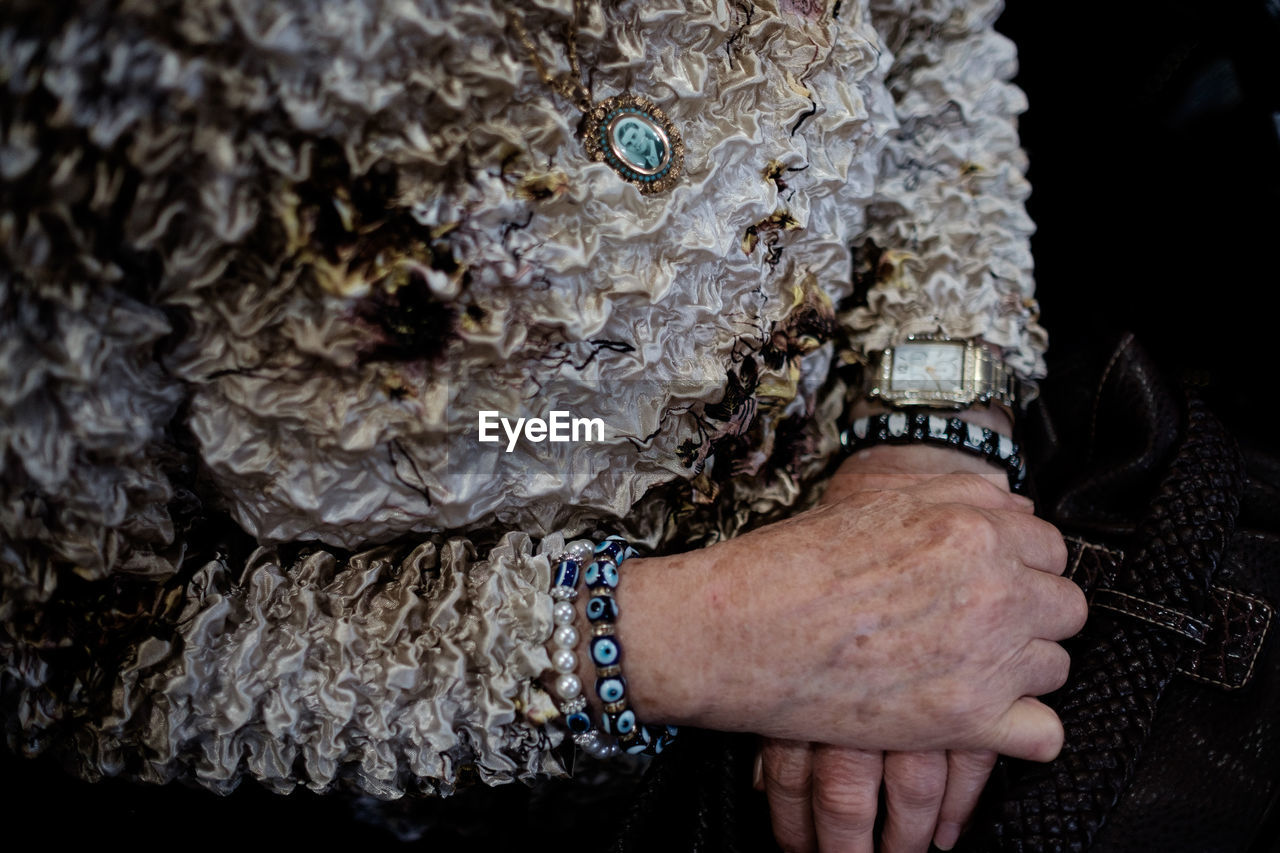 Midsection of woman wearing evil eye beads bracelet
