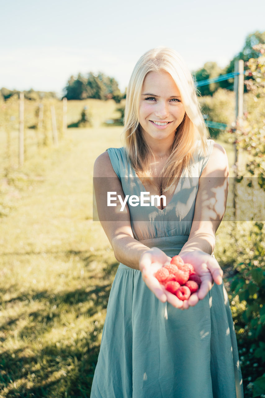 PORTRAIT OF A SMILING YOUNG WOMAN IN FIELD