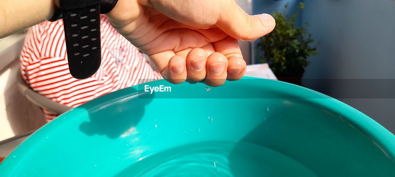 Close-up of water falling from hand in bucket