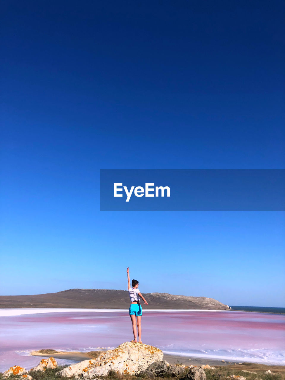 Woman standing on beach against clear blue sky