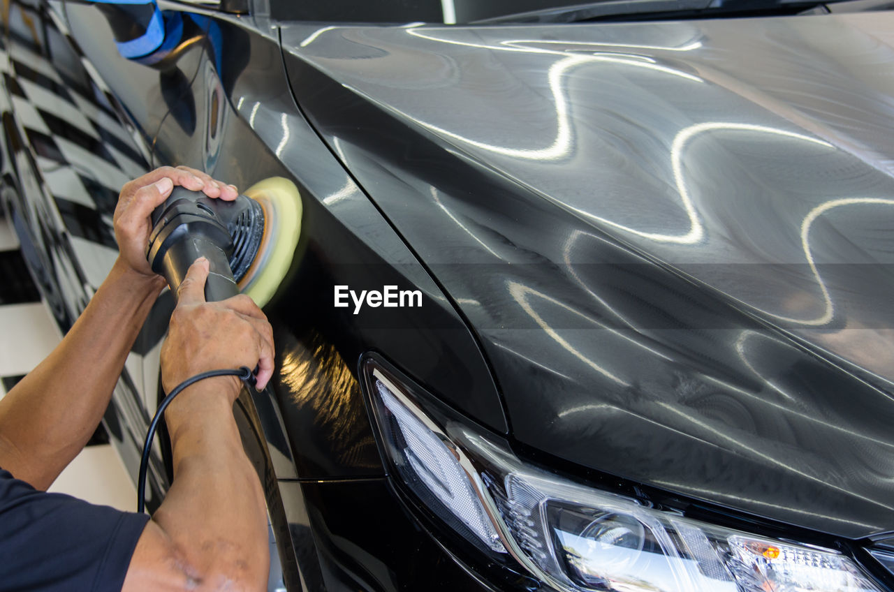 Cropped hand of person polishing car at garage