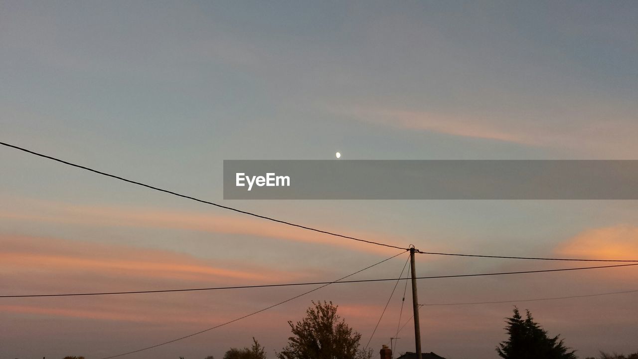 Silhouette power lines against cloudy sky at dusk