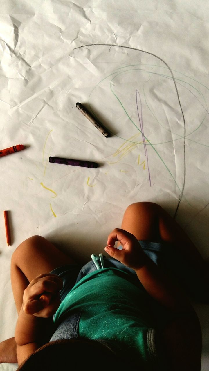 Directly above view of toddler drawing with crayons on paper