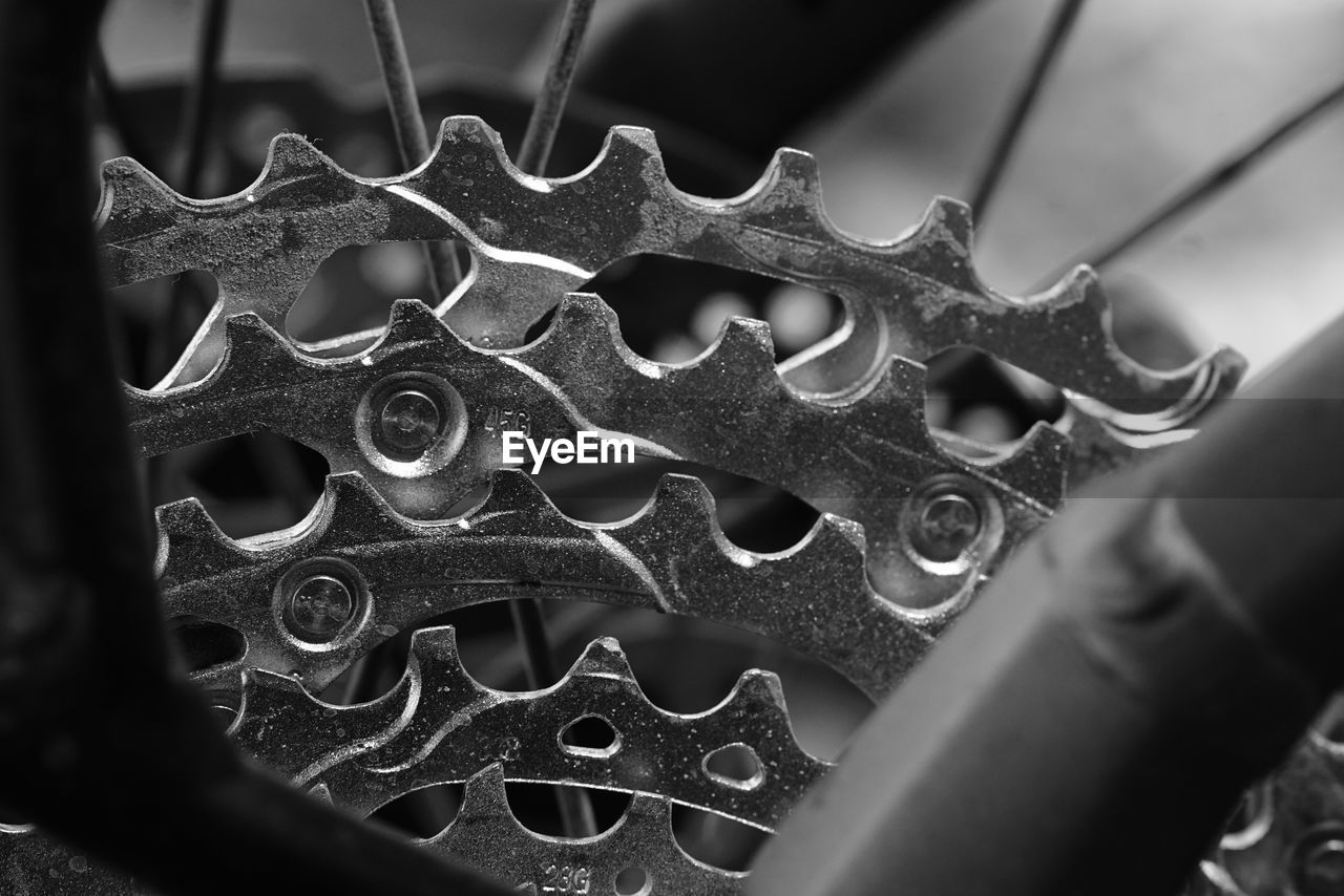 black, black and white, close-up, monochrome, monochrome photography, metal, macro photography, gear, selective focus, no people, wheel, machine part, pattern, bicycle, equipment, iron, indoors, tire