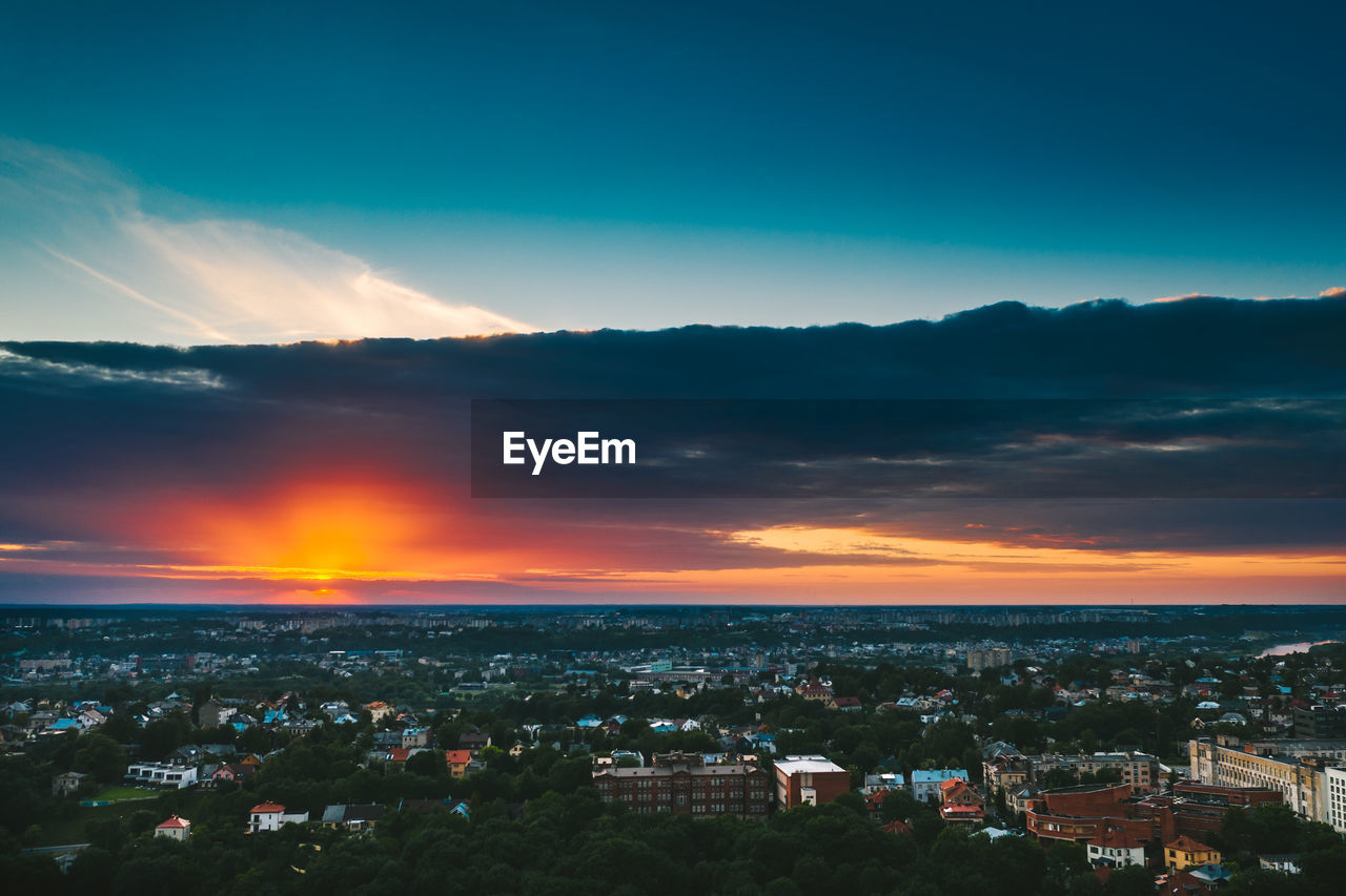 HIGH ANGLE SHOT OF TOWNSCAPE AGAINST SKY AT SUNSET