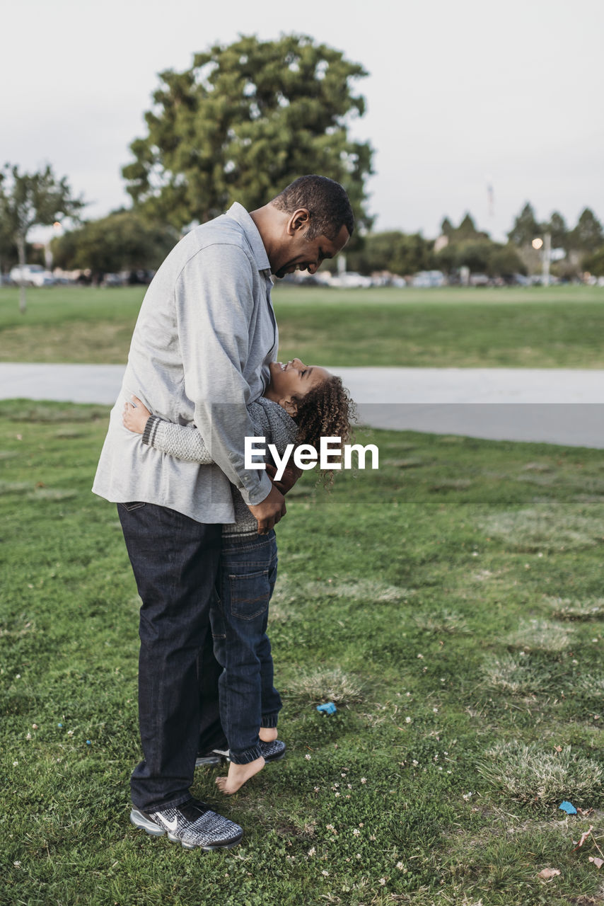 Happy father and son embracing outside at park at dusk