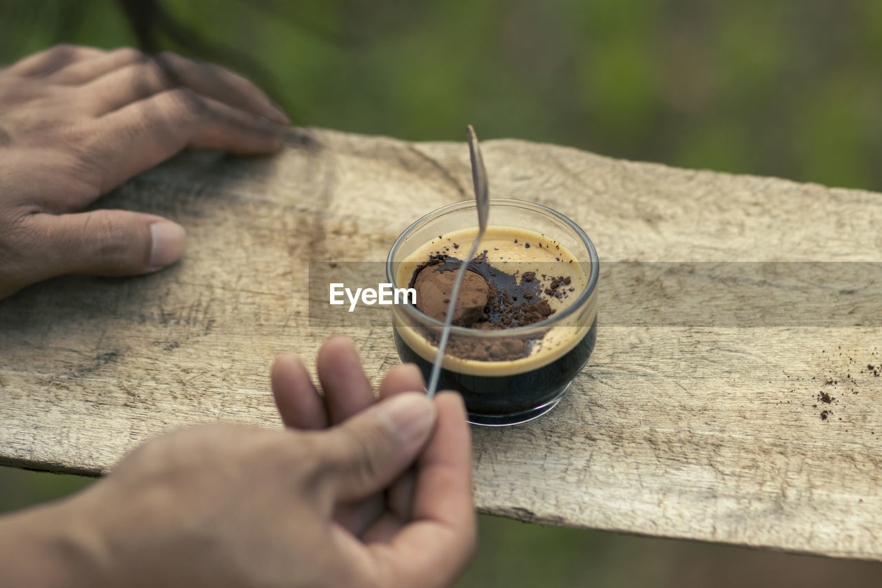 Selective focus cocoa powder in a cup of black coffee in the hand of a man 