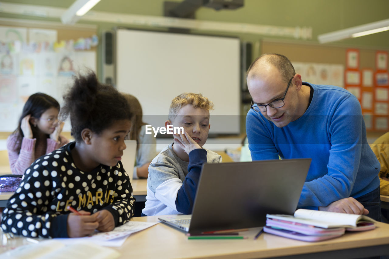 Teacher helping children in classroom