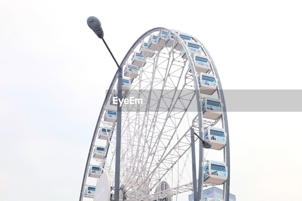 Low angle view of ferris wheel and street light against clear sky