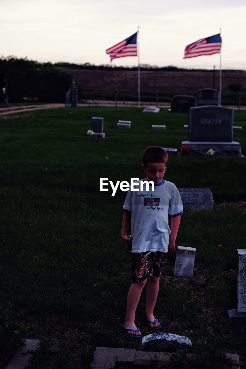 Boy standing by tombstone at cemetery