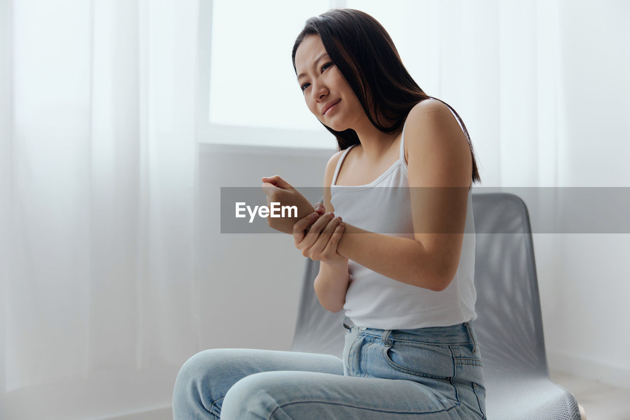 side view of young woman sitting on bed at home