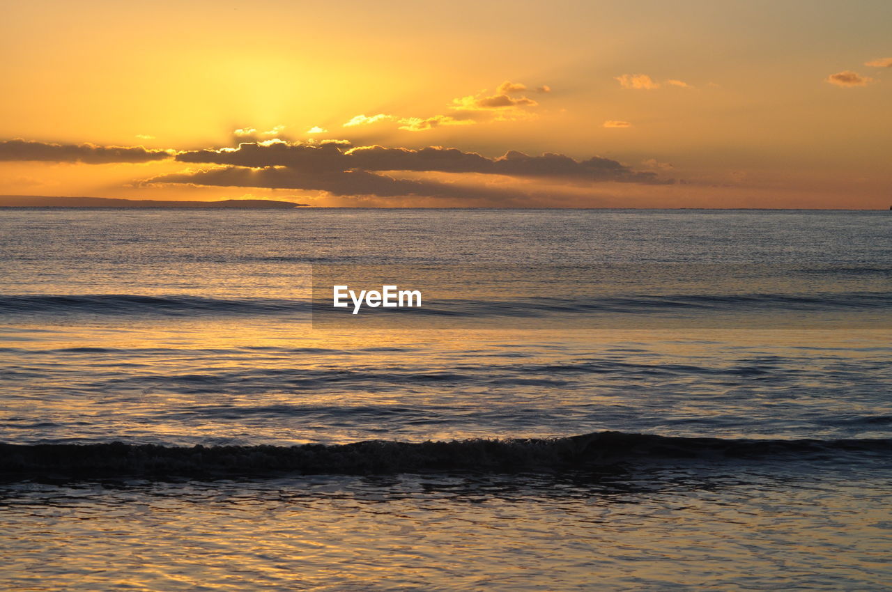 Scenic view of sea against dramatic sky during sunset