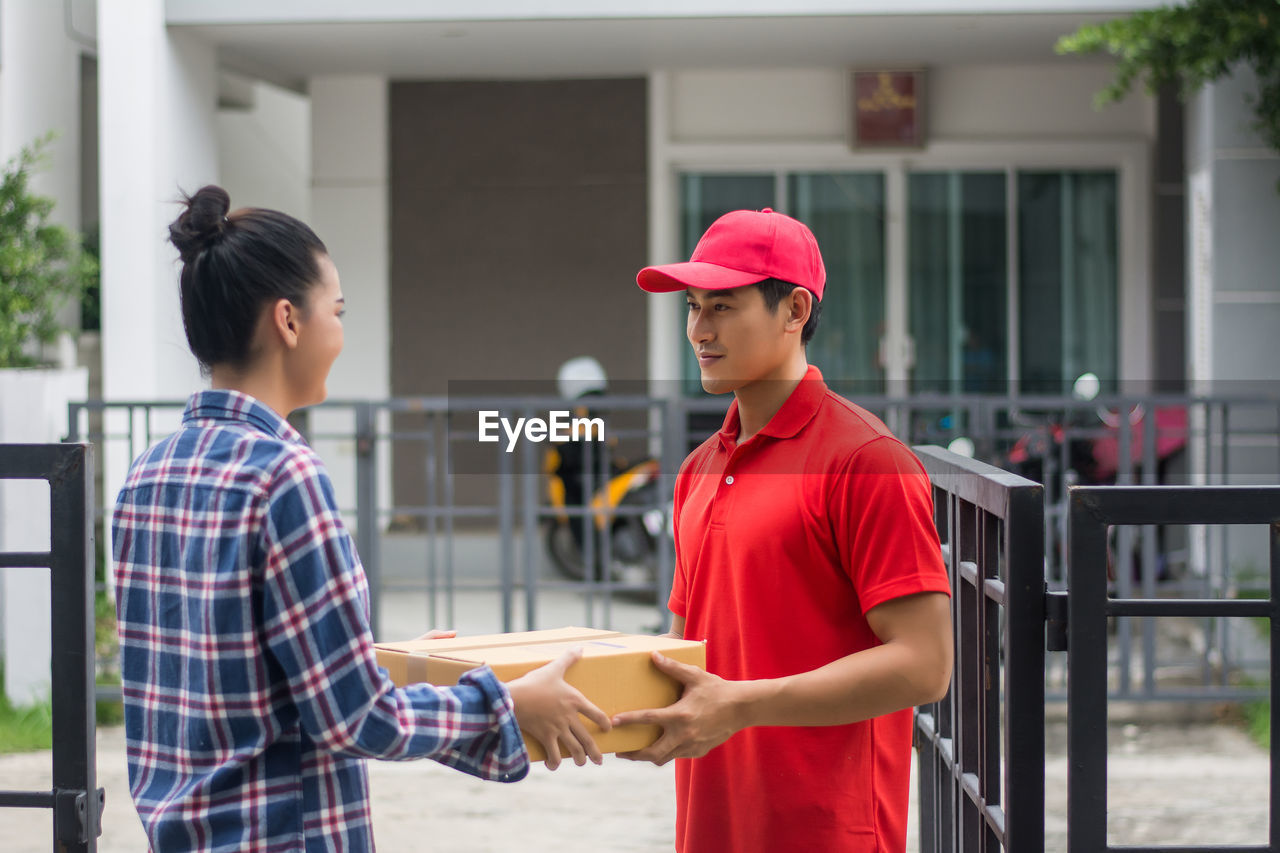 Man delivering package to female customer at gate