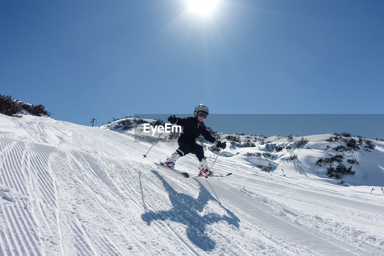 Full length of boy skiing on snow field against sky