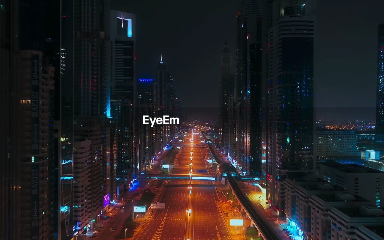 Illuminated street amidst buildings at night