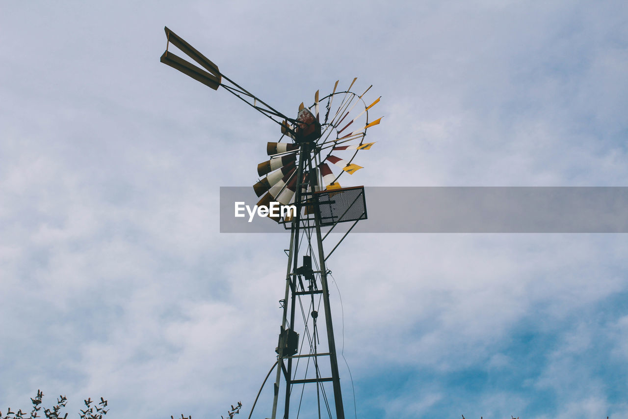 Low angle view of american-style windmill against cloudy sky