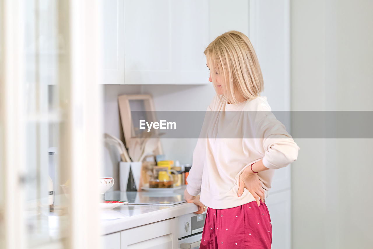 Side view of woman standing at home