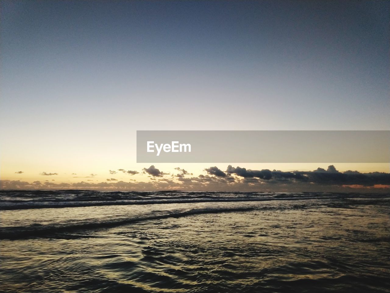 SCENIC VIEW OF BEACH AGAINST CLEAR SKY DURING SUNSET