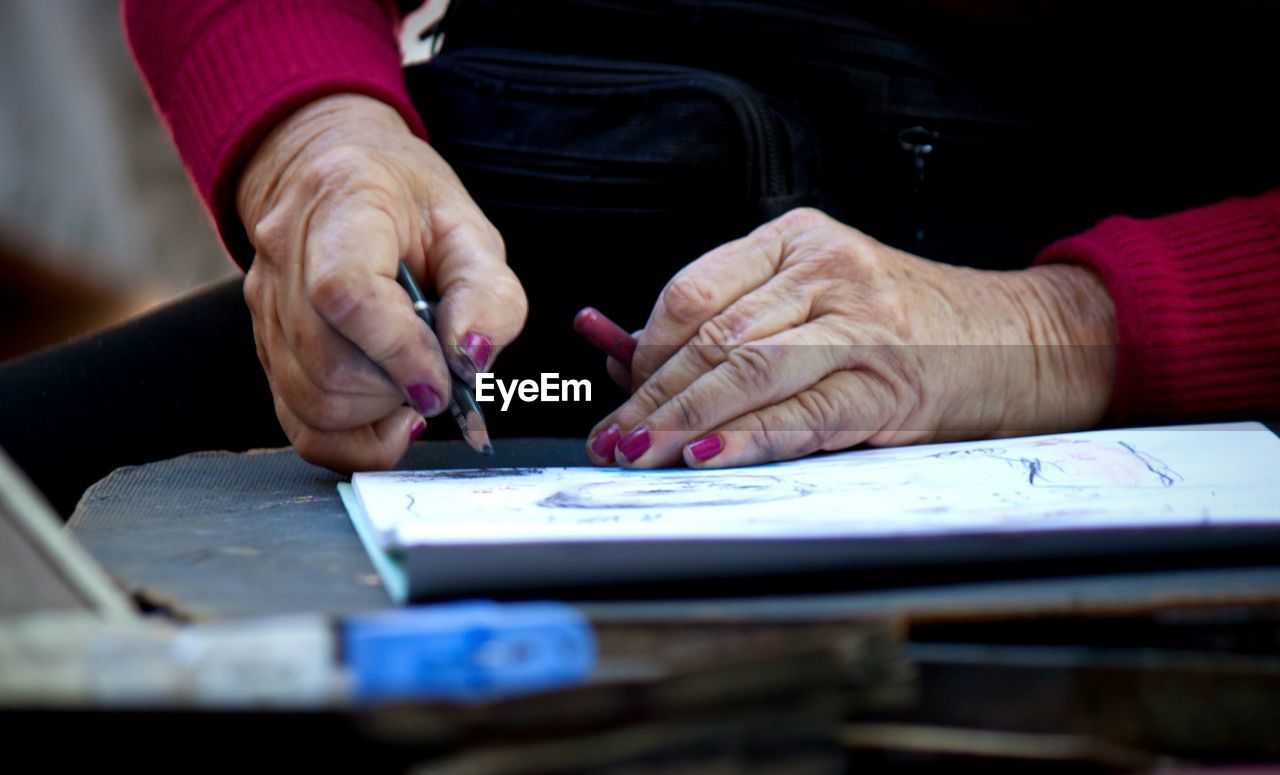 Cropped image of mature woman drawing at table