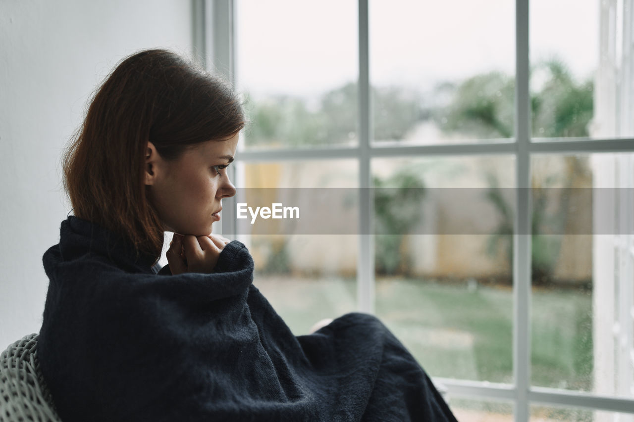 GIRL LOOKING AWAY AGAINST WINDOW