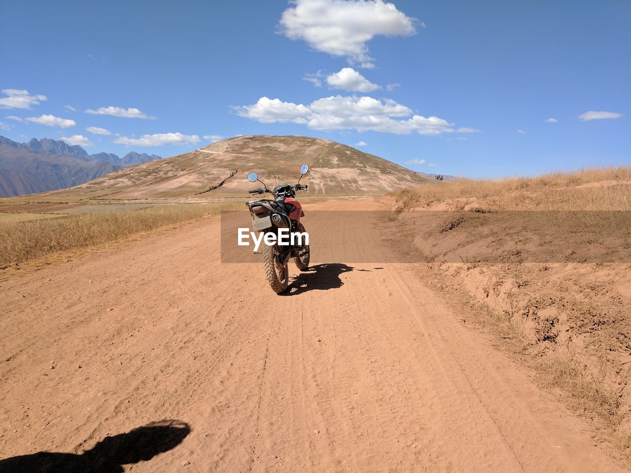 Motorcycle on dirt road against sky