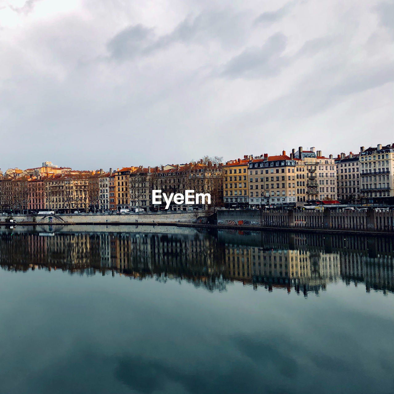 Buildings by river against sky in city